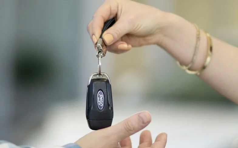 a car key being handed over — article card